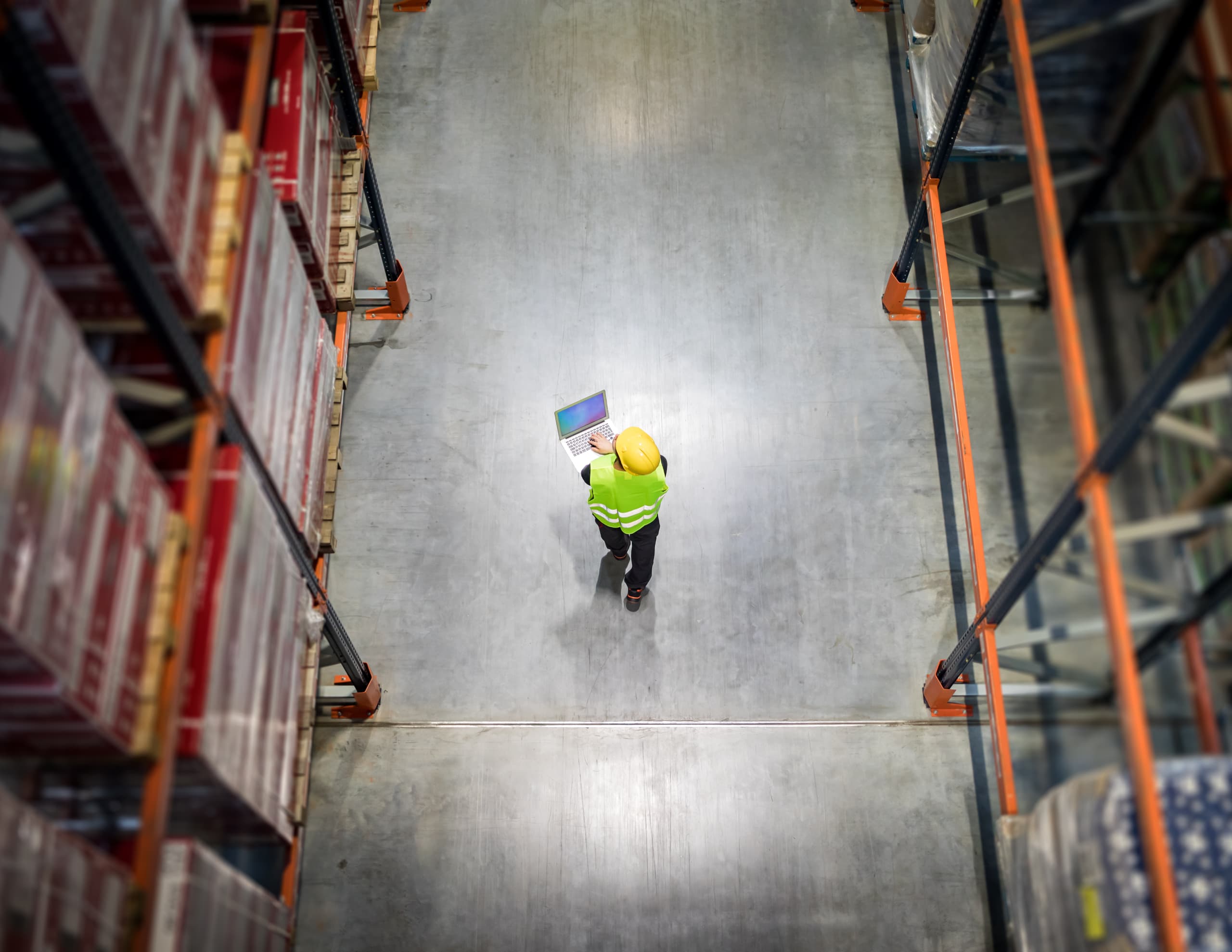 Worker walks through warehouse on laptop