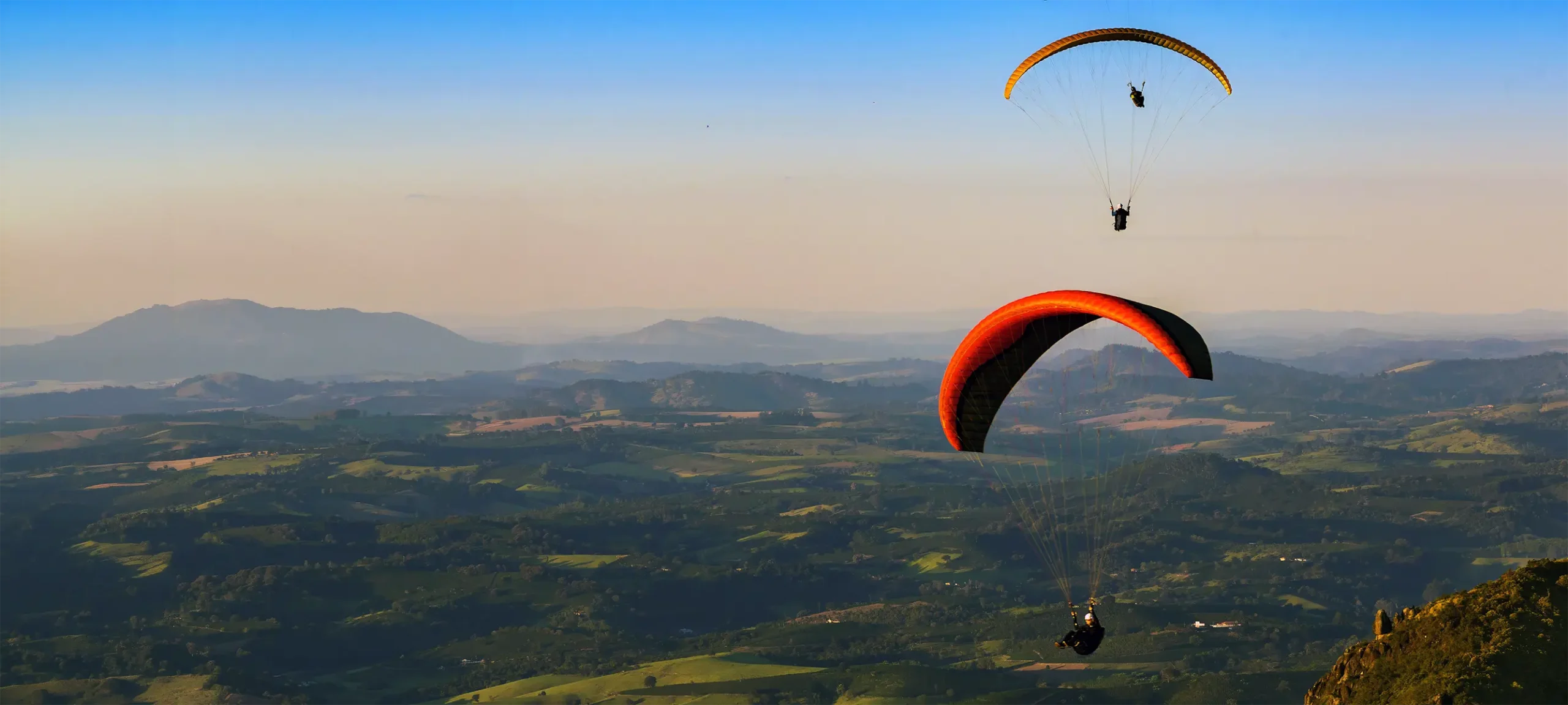 Paragliders over a valley, showing high-tenacity Dyneema shroud lines in extreme sports.