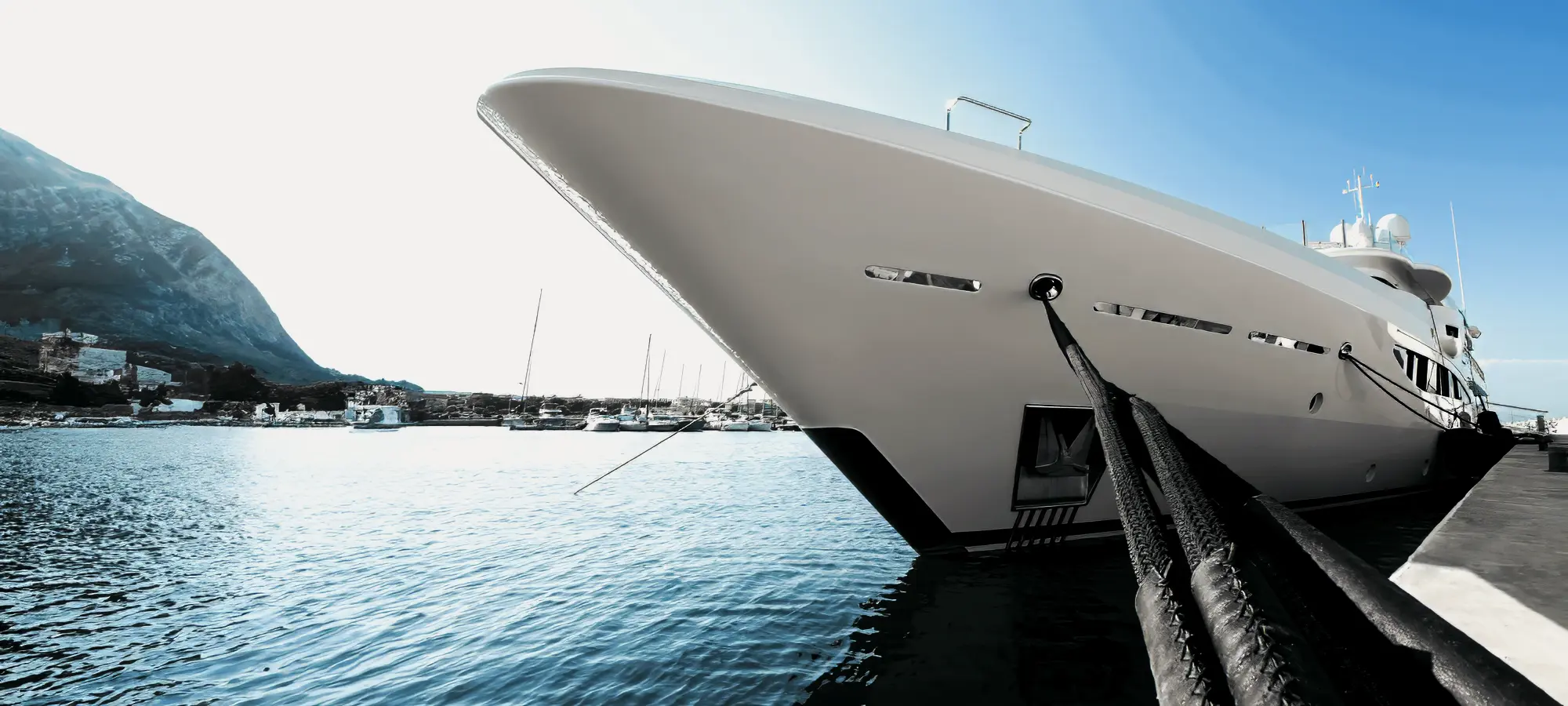 White superyacht moored at a quay with heavy-duty black braided mooring lines for marine resilience.