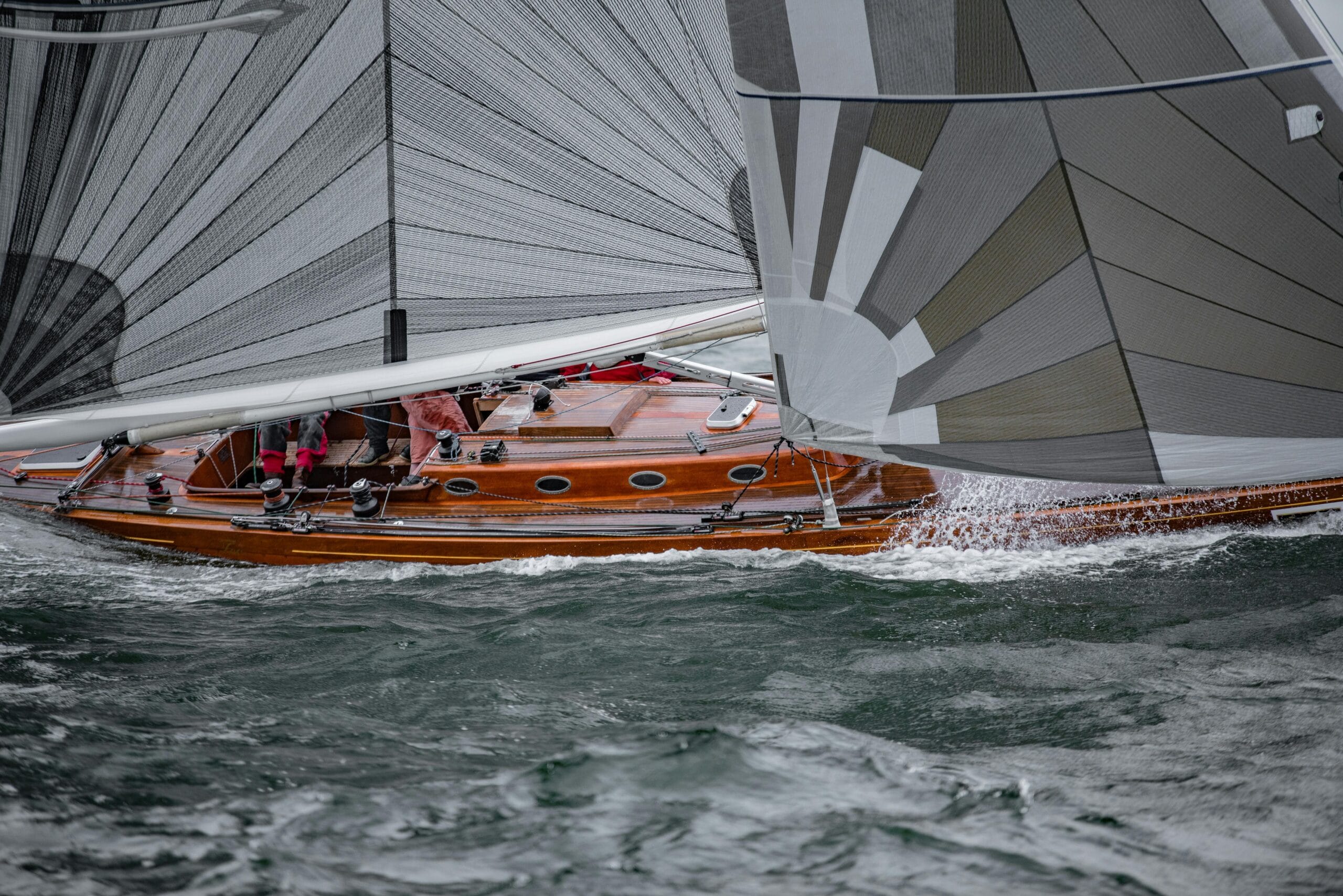 A classic racing yacht on choppy water, featuring high-performance synthetic rigging under tension.