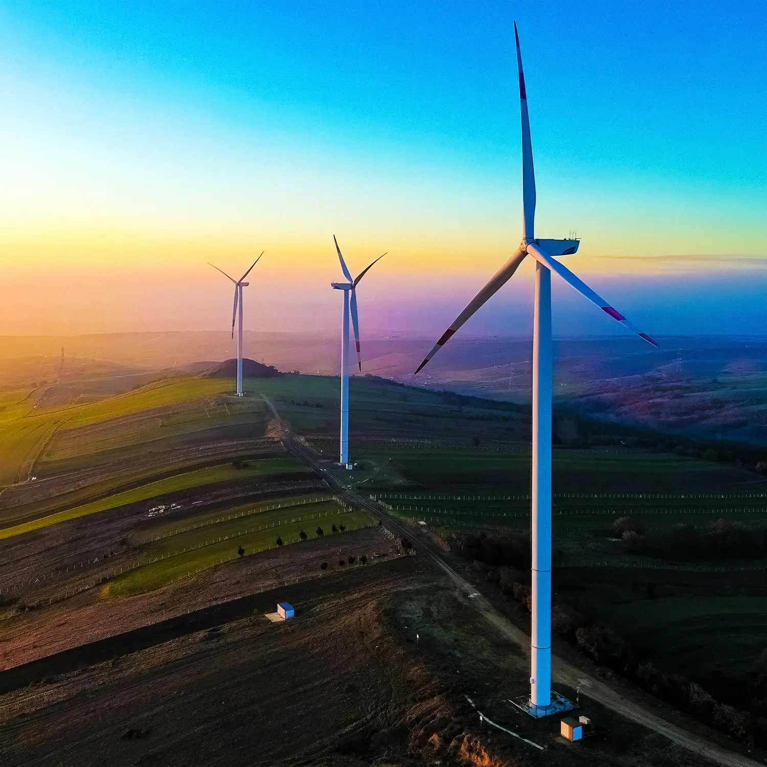 renewable energy wind turbines on a hill top at sunset