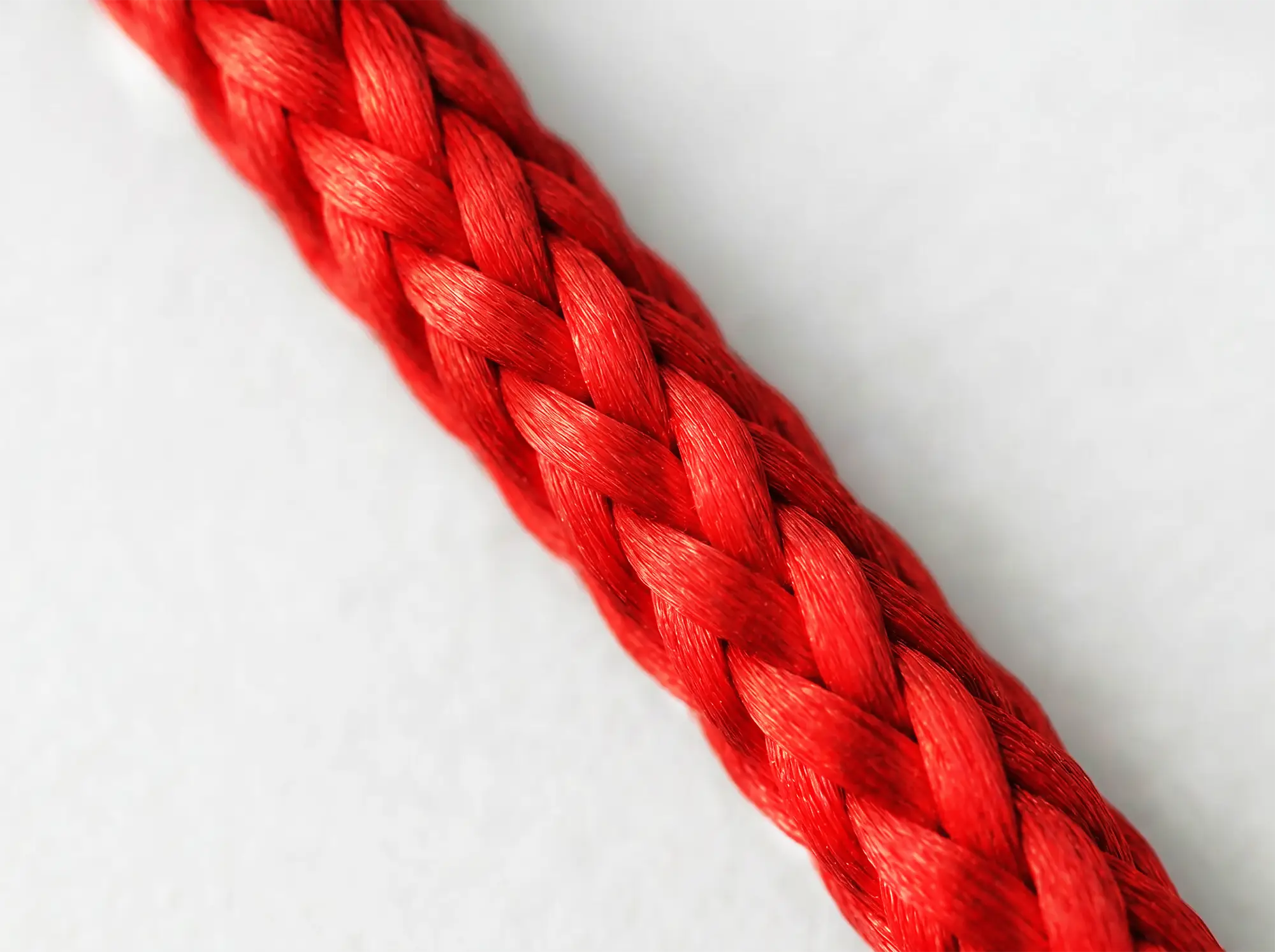 Macro photograph of English Braids 12-Strand Polyester rope showing red PU coated strand construction and diamond braid pattern