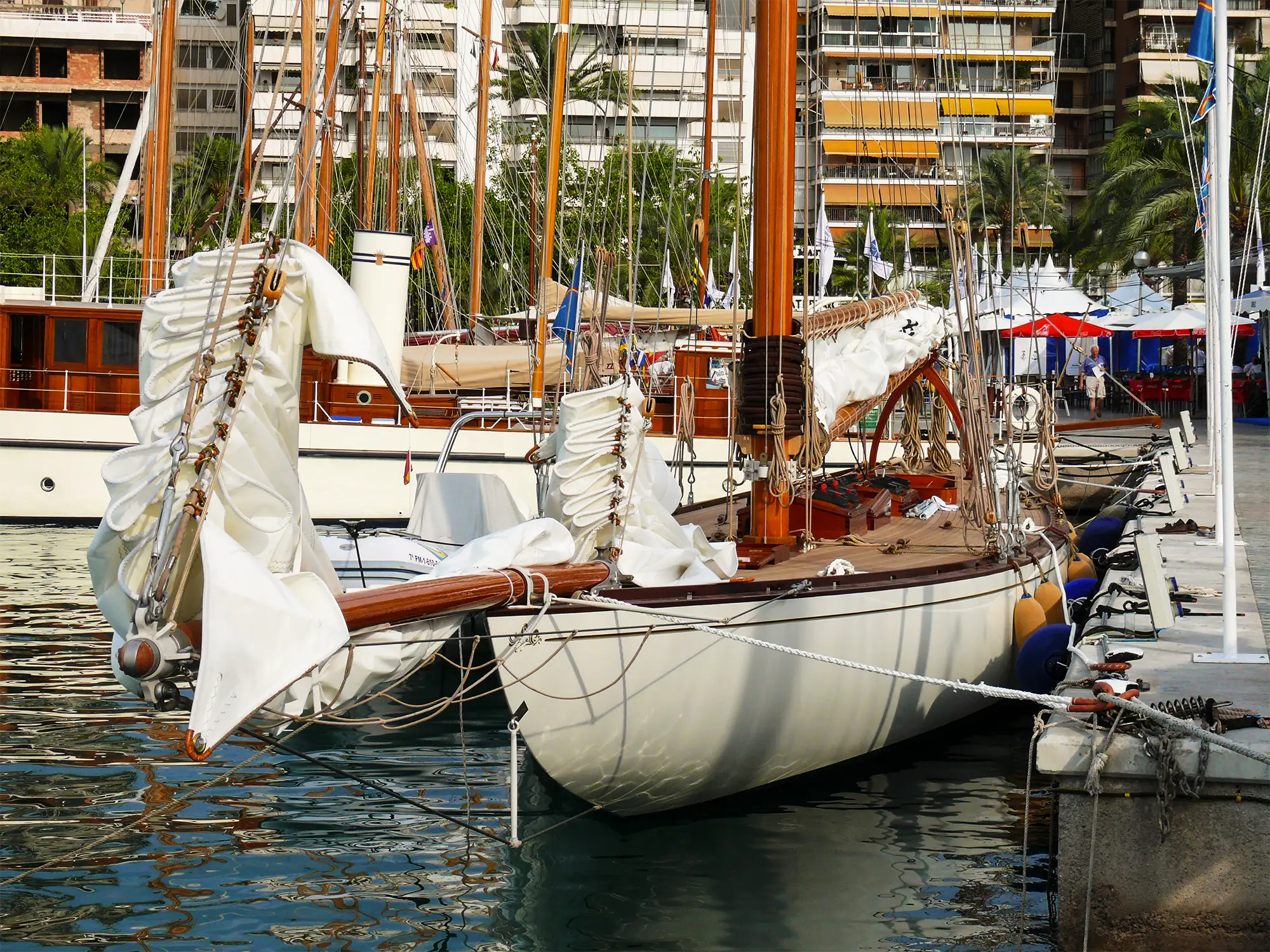 Classic wooden sailing yacht docked in marina with traditional buff rope rigging and running rigging clearly visible