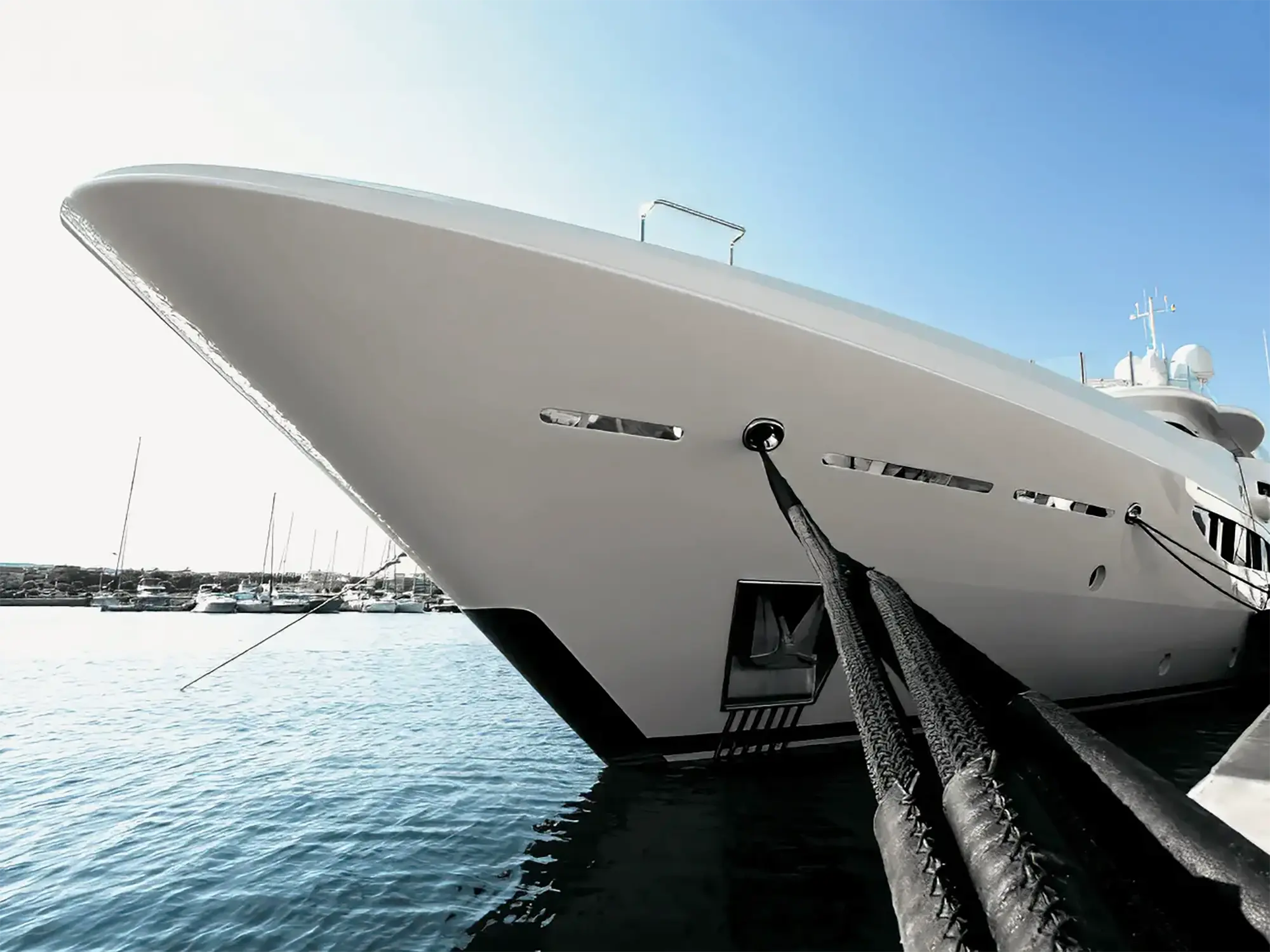 White superyacht moored at a quay with heavy-duty black braided mooring lines for marine resilience.